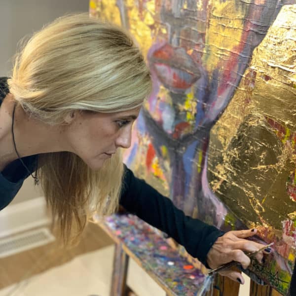 Ronit Galazan touching up a gold foil painting in her studio.